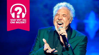 Tom Jones sjunger i en mikrofon som han håller i handen.