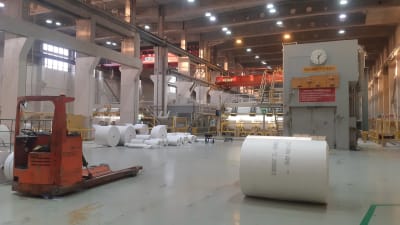 Stora pappersrullar på ett fabriksgolv.