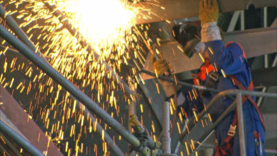 Svetsare arbetar med metall i en industrihall.