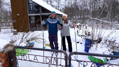 En man och en kvinna står på skidor i en trädgård.