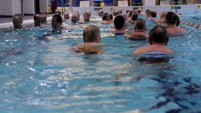 Pensionärer vattenlöper i en simhall.
