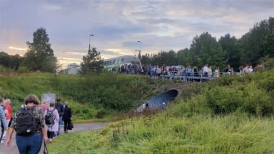 Kö av personer som vandrar ut från ett tåg. 