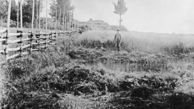 Ett svartvitt foto av en pojke som står vid källan Levänluhta.