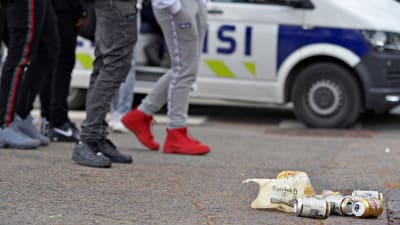 Ölburkar som ligger på marken framför ungdomar. 