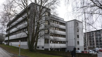 En vit flervåningsbyggnad med mörka fönsterkarmar. 