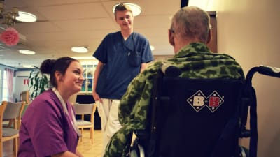 Matilda och Abbe talar med en äldre person som sitter i en rullstol i Almahemmet.