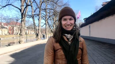 en kvinna i vårkläder står i vårväder vid aura å