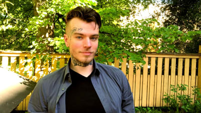 en ung man med tatueringar i ansiktet och på halsen i somrigt väder