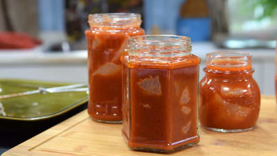 Konserverad mört i tomatsås i glasburkar innan ugnen på en skärbräda