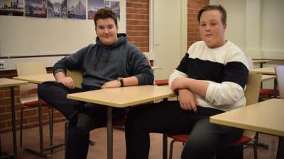Atte Hellbom och Joacim Oksanen sitter i ett klassrum med armarna vilande på var sin pulpet.