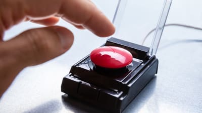 En stor röd knapp och en hand på väg att trycka på knappen.