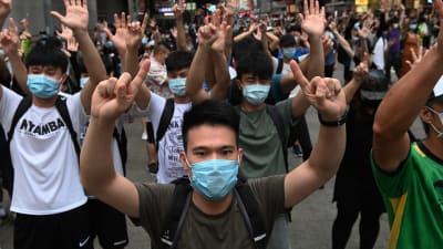 Demonstranter med munskydd och händerna upphöjda.