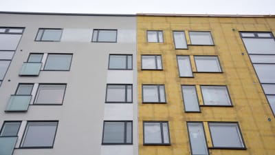 En husfasad, hälften intäkt, hälften med isoleringen framme.