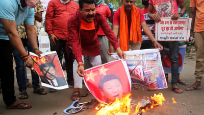 Män bränner bilder på den kinesiska presidenten Xi Jinping.