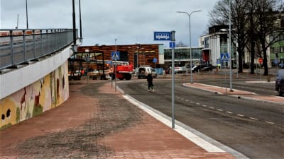 Uppfarten på en bro intill en stenbelagd gata och några skyltar för bussar.