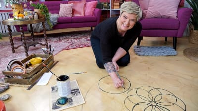 Glad kvinna målar cirklar på ett golv.