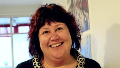 Annalena Sjöblom som är verksamhetsledare för Röda Korset i Åboland, här i halvkort vinrött-svart hår och med ett brett leende.