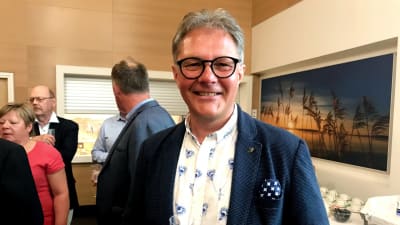 en man i kostym håller ett glas bubblande vin i handen