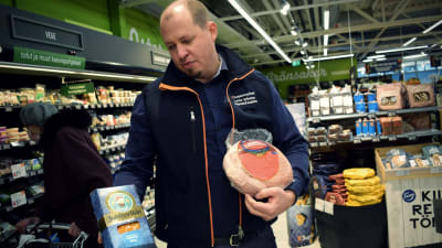 Köpman Tobias Eriksson håller en mindre skinka och en vegansk julskinka i händerna i sin matbutik.