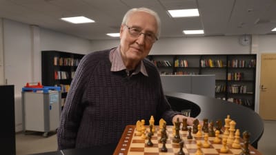 Helge Hedman i Zachariasskolans bibliotek. Han står bredvid ett schackspel.
