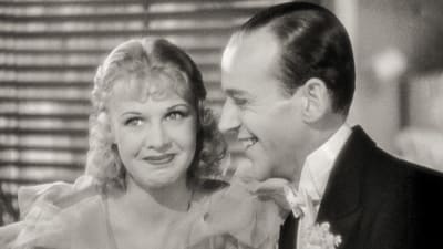 Ginger Rogers hymyilee leuka mutrussa, vieressä häntä kohti leveästi hymyilevä Fred Astaire.