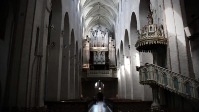 Insidan av Åbo domkyrka med vy över predikstolen och orgeln och kyrkbänkarna.