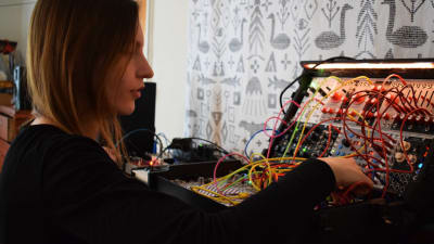 Laura Naukkarinen plockar med sladdar i sin elektroniska musikapparat.