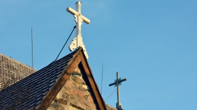 Två vita träkors på taket av en kyrka.
