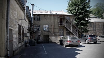 Gränden vid Österbladska tomten. Syns halvfallna hus och några bilar på parkeringen.