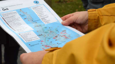 En person med gul rock håller i en karta över Örö.