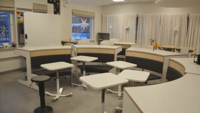 Modern lärmiljö med vita skolbänkar.
