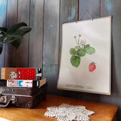 En plansch med en handmålad jordgubbsplanta med en handtryckt text.