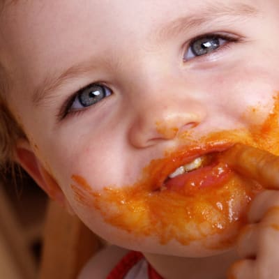 Pieni lapsi suun ympärys tomaattikastikkeessa
