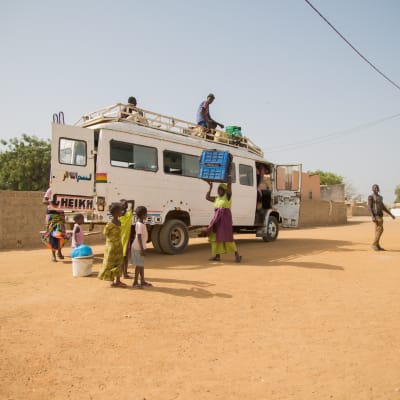 pikkubussia lastataan kylänraitilla Senegalissa
