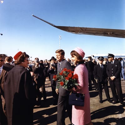 John F. Kennedy ja Jacqueline Kennedy lentokentällä. Heidän ympärillään on ihmisiä.