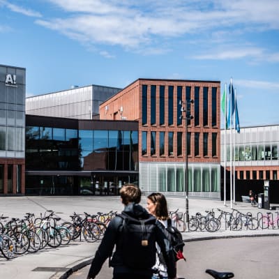Aalto-universitetet i Esbo, ett stort antal cyklar och två personer i förgrunden.