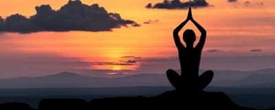Person som mediterar i solnedgången.