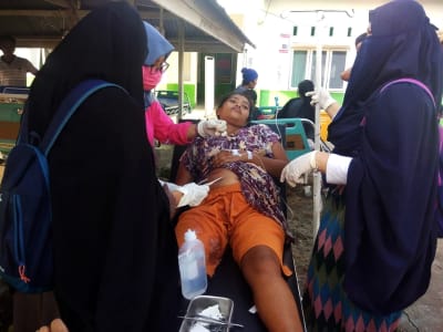 Kvinna som skadats i jordskalvet i Donggala får första hjälp.