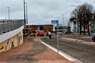 Uppfarten på en bro intill en stenbelagd gata och några skyltar för bussar.