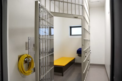 en fängelsecell med traditionellt galler som väggar och en enkel gul säng
