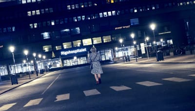 En nattbild där vi ser Karen (Bodil Jørgensen) som går mot huvudingången till Rigshospitalet.
