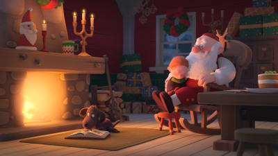 Joulupukki istuu keinutuolissa lapsi sylissään takan edessä.