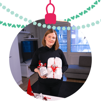 Rantanen esittelee elintarvikepakkauksista tehtyjä lahjapaketteja. Valokuva on muokattu joulupallon muotoiseksi.