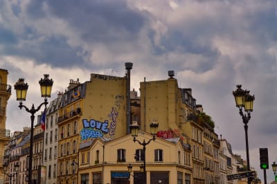 Korttelin päätytalot Pariisissa kahden tien risteyksessä, katulyhdyt talon päädyn molemmin puolin.