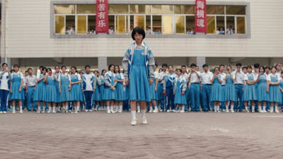 Flicka står framför folkmassa på skolgården