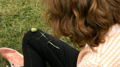 En kvinna har format två kors av grässtrån på sitt byxben.