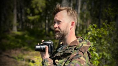 En man med kamera i handen.