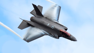 Ett F-35 jaktplan flyger diagonalt genom bilden.