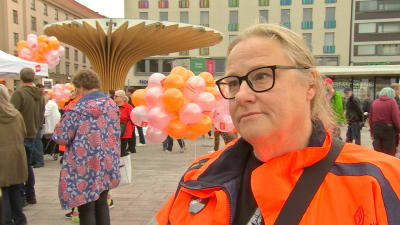 Kvinna i glasögon och orangefärgad jacka på Salutorget i Åbo 