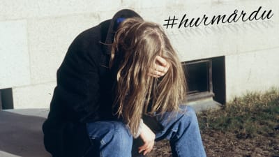 Deprimerad människa sitter böjd framåt.
